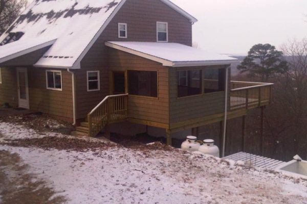 Shingled house with screen porch and deck with dusting of snow